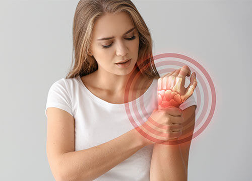 Young woman looking distraught holding her wrist in pain